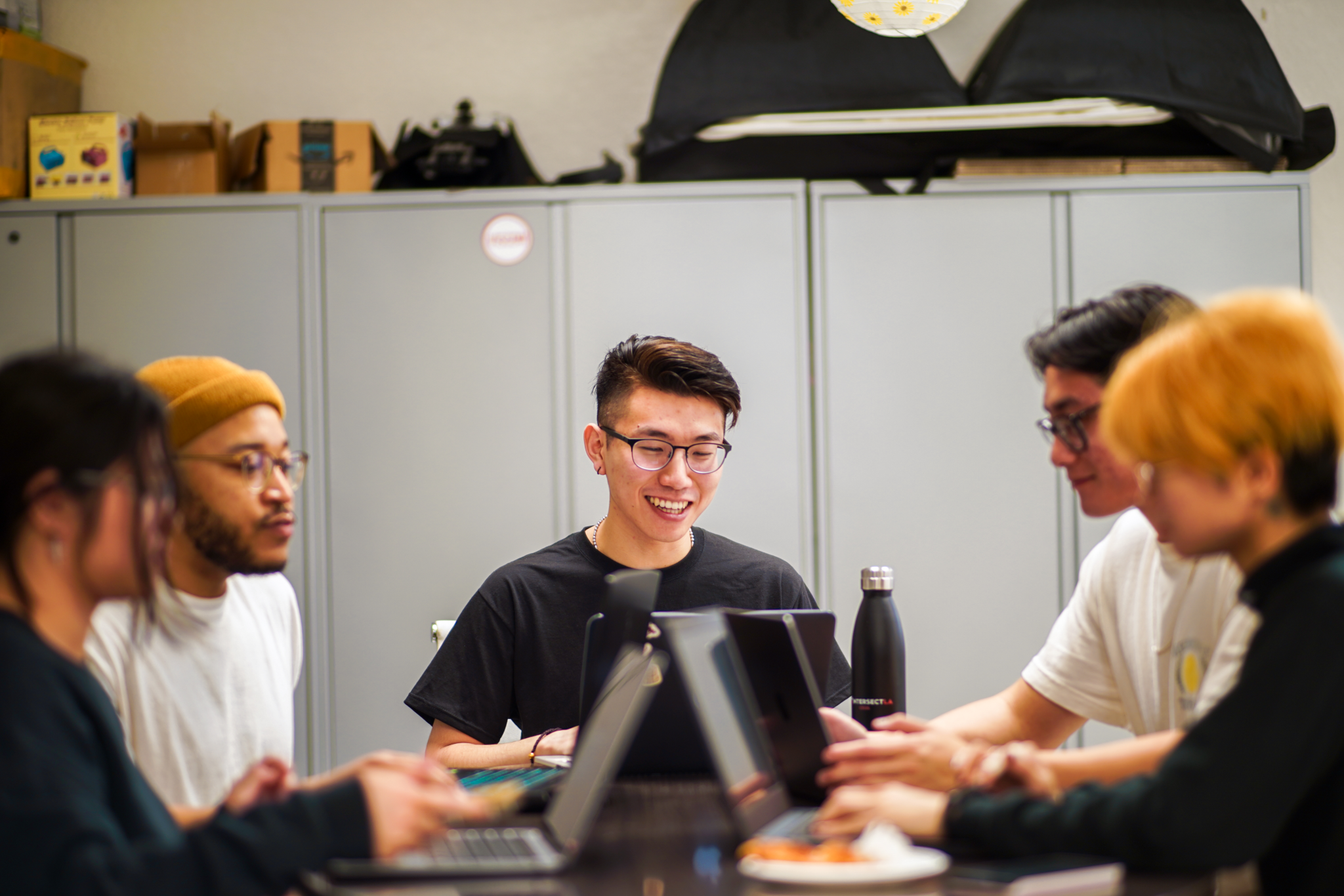 at the ixla office, a student works on their computer as two other students nearby chat